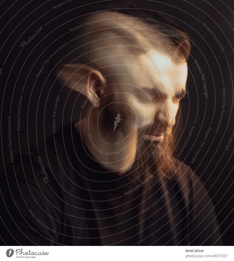 Double exposure artistic portrait of a handsome hipster male worried and angry about something with cinematic light. Dark background with dark tones. Artistic mental health concept. Demons inside.