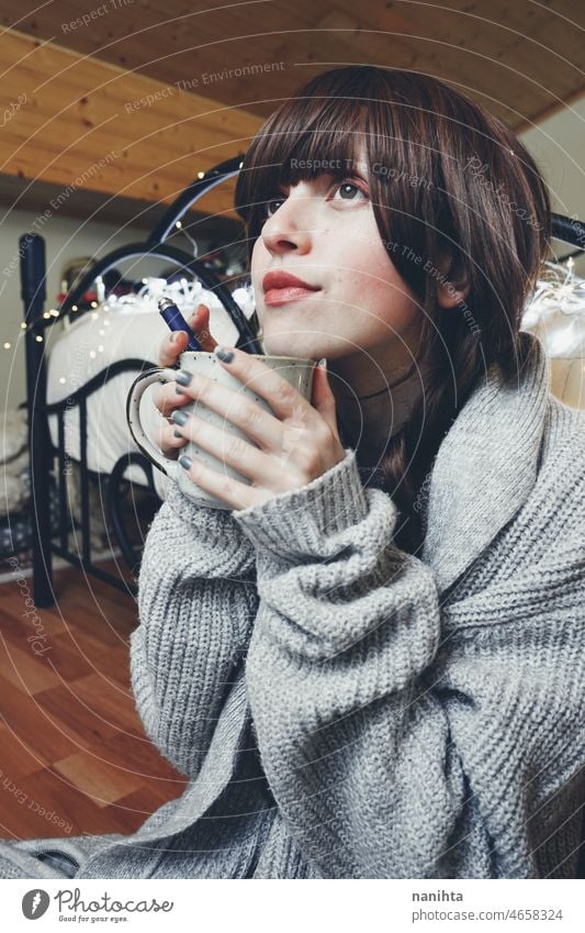 Young and dreamy woman enjoying a cup of coffee home warm tea winter autumn mood moody portrait comfort quiet tranquility life lifestyle comfy cute brunette