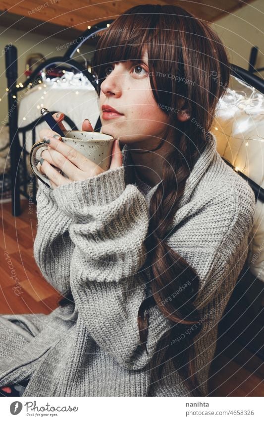 Young and dreamy woman enjoying a cup of coffee home warm tea winter autumn mood moody portrait comfort quiet tranquility life lifestyle comfy cute brunette