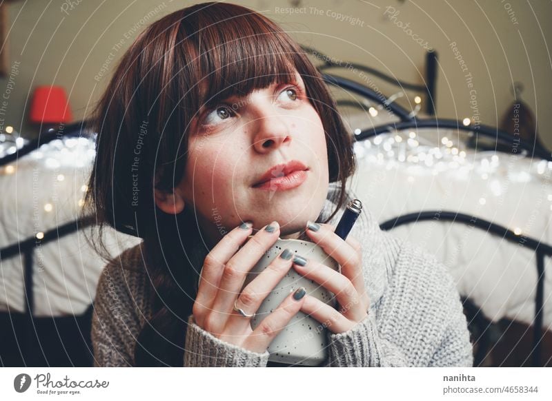 Young and dreamy woman enjoying a cup of coffee home warm tea winter autumn mood moody portrait comfort quiet tranquility life lifestyle comfy cute brunette