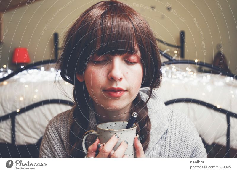 Young and dreamy woman enjoying a cup of coffee home warm tea winter autumn mood moody portrait comfort quiet tranquility life lifestyle comfy cute brunette