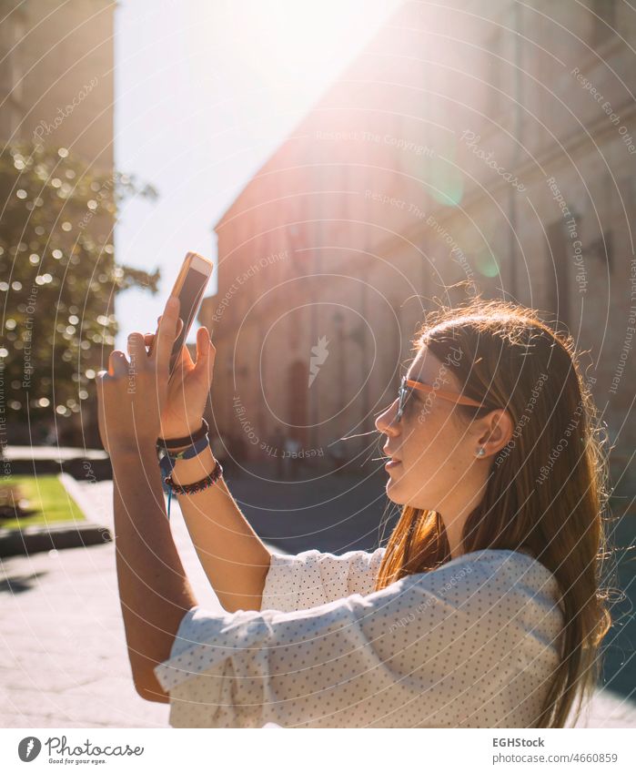 Young female visiting an ancient city in spain taking a picture of a Salamanca monument with her mobile phone at sunset one person historic woman tourism