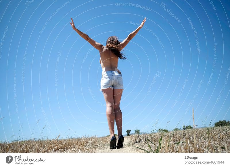 Back view of a unrecognized topless woman with arms raised in countryside female naked brunette nature outdoor adult person day horizontal beauty summer back