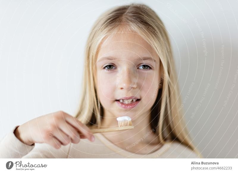 Cute little girl holding hands eco bamboo toothbrush on beige background. Sustainable living concept. Save the Planet for our children toothpaste tooth brush