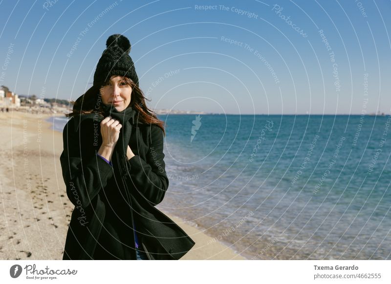 Woman with hat and coat on the beach on a sunny winter day 45-50 years woman. mature warm femininity headshot outside seasonal serious solitude affection