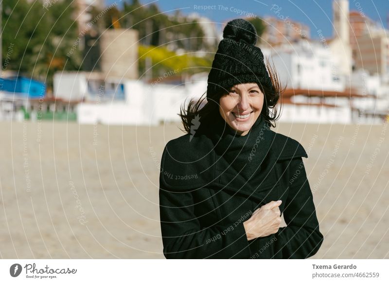 Smiling woman in hat and coat on the beach on a sunny winter day 45-50 years mature portrait closeup lonely carefree enjoy friendly peaceful running sad smile