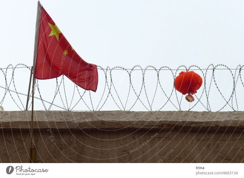 Chinese flag in front of barbed wire with red lantern China chinese flag Barbed wire regime Lampion Xinjiang penned Threat gloomy Mistrust Watchfulness