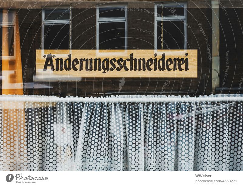 The sign says that behind this shop window with dainty curtain is an alteration tailor shop tailoring Dinest performance service Tailor's shop Craft (trade)