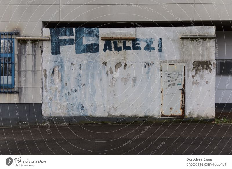 Facade with window and door on old hall with soccer fan graffito Building Hall Old forsake sb./sth. neglected Gloomy Graffito Blue writing From outside