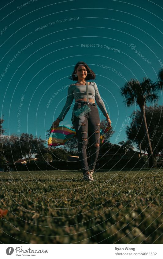 Young Spanish woman in a park with colorful scarf. one person daydream freedom beauty playground grass blue sky clear dance tree happiness windy sunny pose