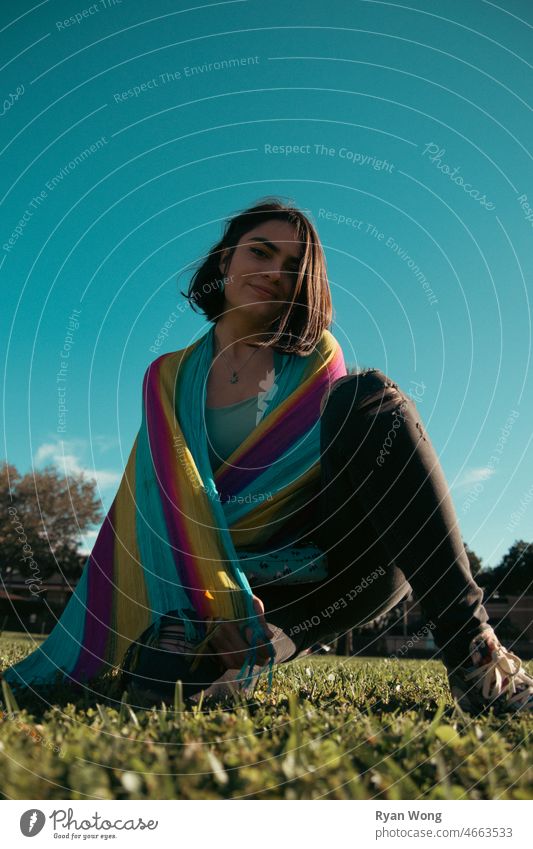 Young Spanish woman in a park with colorful scarf. one person daydream freedom beauty playground grass blue sky clear dance tree happiness windy sunny pose