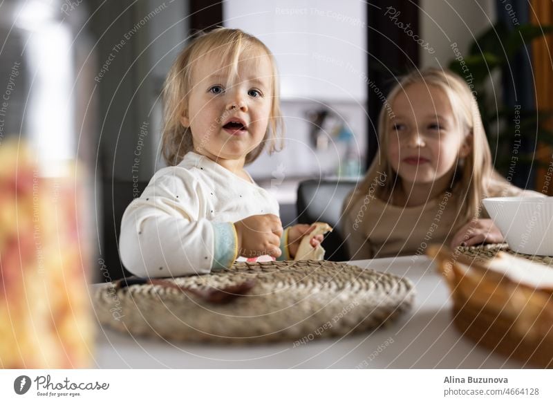 Cute caucasian siblings sitting at table on kitchen early morning and preparing breakfast with colorful cornflakes and milk. Kids enjoying life with healthful food, healthy lifestyle concept