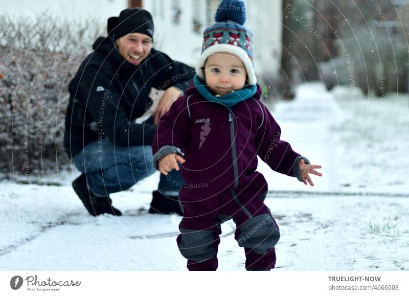 A little boy just 1 year old discovers walking alone and the first snow of his life while his dad watches in the background and is happy Toddler walk alone