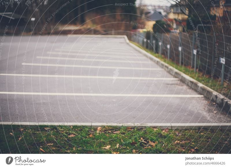 Empty parking spaces Parking spaces Parking lot Places Fence Meadow Mobility Deserted Colour photo Exterior shot Signs and labeling Town Street unused Asphalt