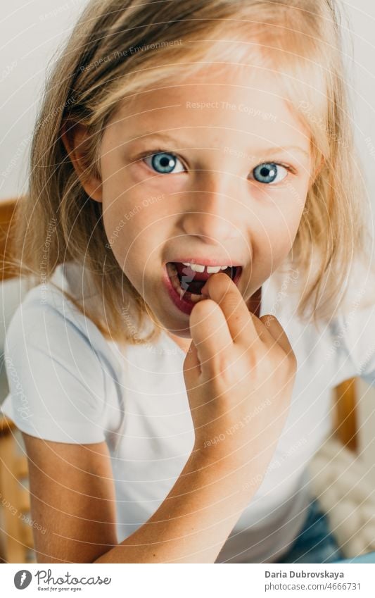 7 year old blonde girl with blue eyes baby tooth milk tooth smiling oral dentistry finger little happy kid smile childhood face background young caucasian cute