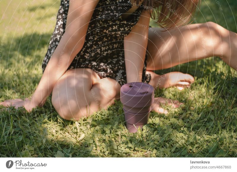 Faceless shot of woman sitting in grass with collapsible eco friendly cup in front of her Recycling Beverage drink Cup Green Snack bar Portable no waste