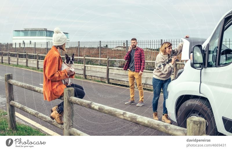 Female mechanic fixing the camper van of a couple on a trip woman female car repair break down hood engine lantern repairwoman service person people bonnet