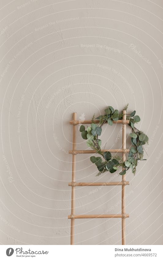 A staircase and green wreath near beige wall, minimalist background with copy space top. Minimal background scandinavian interior style Stairs natural floral