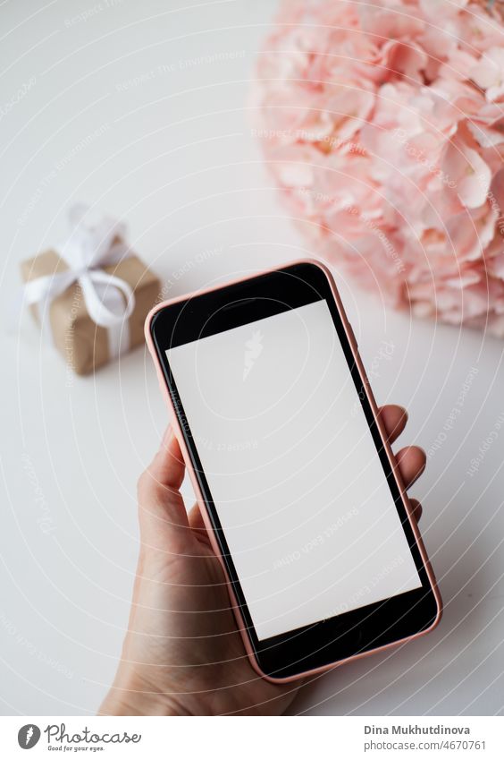 Valentines day, Mobile phone in pink case near pink hydrangea flower and small gift box with ribbon. Surprise for Valentine's Day, sending romantic love message to valentine on mobile phone.