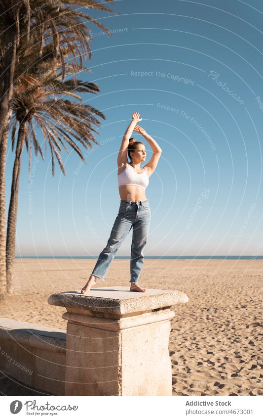 Fit woman on stone pillar feminine embankment waterfront fit figure coast beach leisure sea female top shore seaside nature summer barefoot concrete column lady