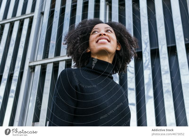 Cheerful black woman near green wall street style city feminine appearance construction smile building female fashion african american lady town design charming