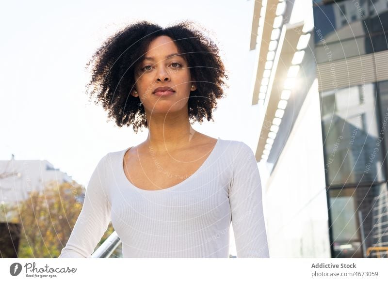 Serious black woman on stairs in city street style building urban feminine appearance trendy outfit female modern elegant fashion confident railing