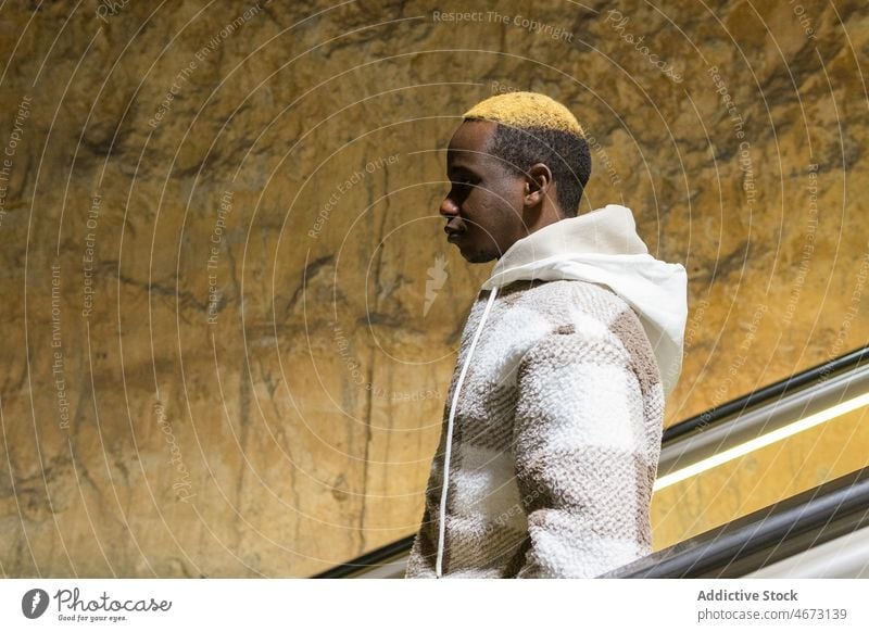 Serious black man on escalator style fashion metro trendy underground moving stairs dyed hair public informal african american modern male shabby wall subway