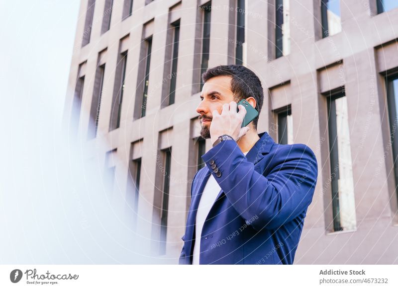 Positive businessman talking on smartphone entrepreneur street city urban building phone call conversation communicate discuss cellphone speak success modern