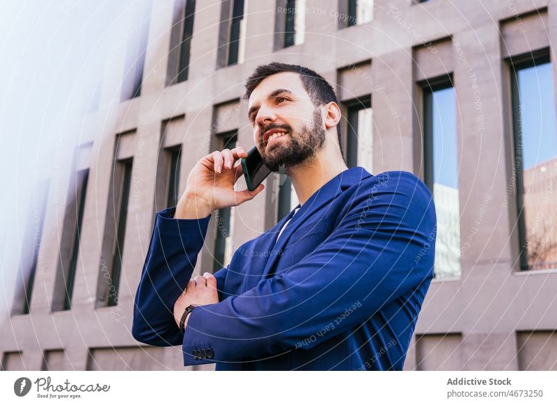 Positive businessman talking on smartphone entrepreneur street city urban building phone call conversation communicate discuss cellphone speak success modern