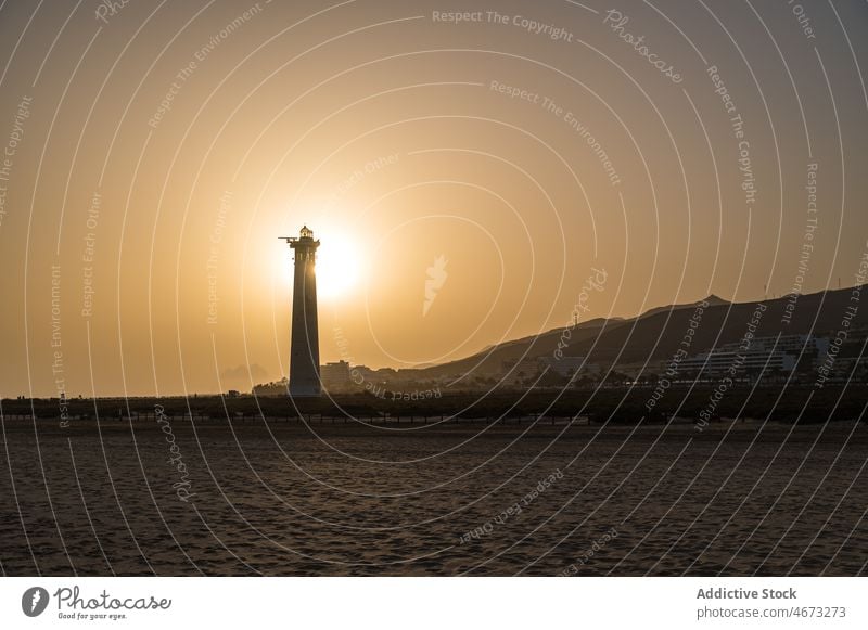 Lighthouse in sunset light on seashore lighthouse beacon evening tower summer beach coast sunlight silhouette scenery sundown tranquil calm peaceful twilight