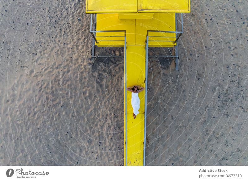 Woman lying on lifeguard tower woman beach sunset seaside yellow vivid summer coast female color bright vibrant calm relax vacation freedom seashore holiday