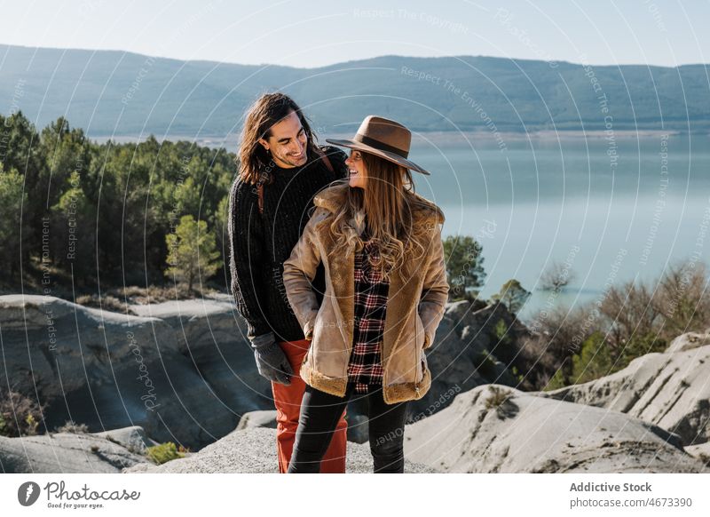 Couple standing on rocky hill couple lake shore nature landscape contemplate explore boyfriend girlfriend together cloudless sky blue sky environment pond