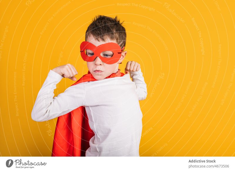 Boy in superhero outfit showing muscles boy child success victory achieve winner costume studio portrait kid courage brave power ambition mask bicep confident