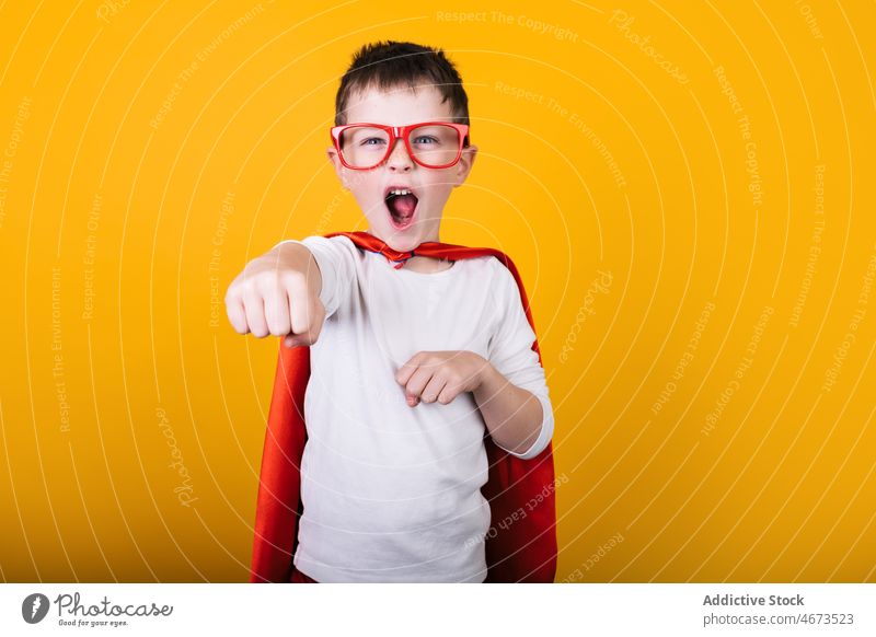 Playful boy in superhero uniform pretending to fly child flight clench fist scream costume portrait studio power kid courage confident cape brave strong