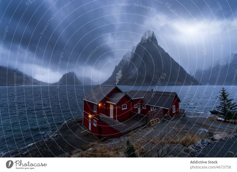 Stormy sky above sea and rocky shore with cottages stormy mountain nature breathtaking norway island lofoten water cliff coast wave Reine scenic landscape