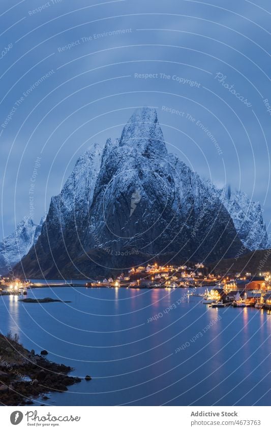 Amazing view of snowy mountains and village located at bottom range settlement house sunset highland landscape picturesque lofoten island norway reine hill