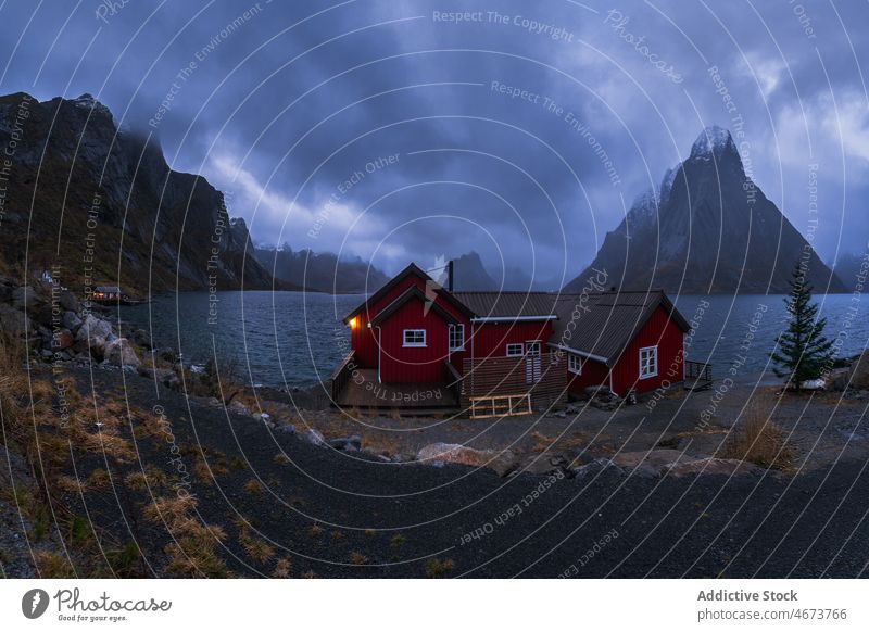 Stormy sky above sea and rocky shore with cottages stormy mountain nature breathtaking norway island lofoten water cliff coast wave Reine scenic landscape