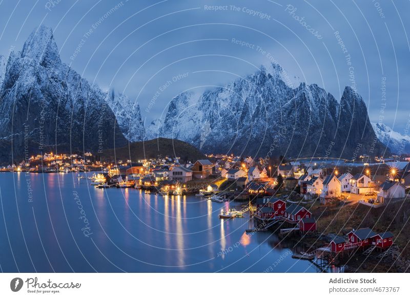 Amazing view of snowy mountains and village located at bottom range settlement house sunset highland landscape picturesque lofoten island norway reine hill