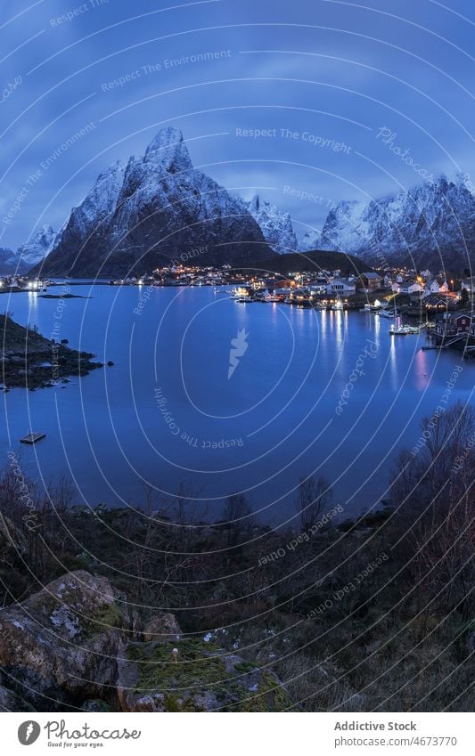 Amazing view of snowy mountains and village located at bottom range settlement house sunset highland landscape picturesque lofoten island norway reine hill