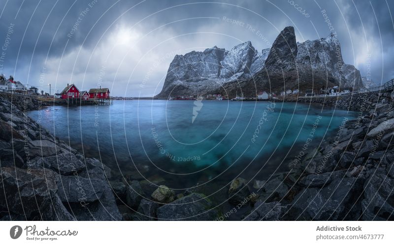 Small coastal village with cottages in bay near snowy mountains settlement sea house shore residential landscape lofoten island norway tranquil fjord scenic