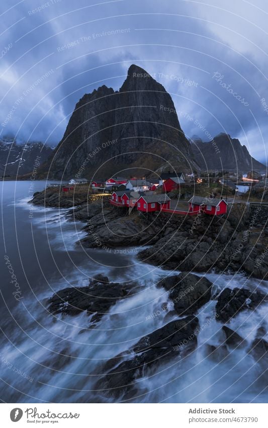 Stormy sea with foam water and rocky shore with cottages stormy mountain nature breathtaking norway island lofoten cliff coast wave Reine scenic landscape