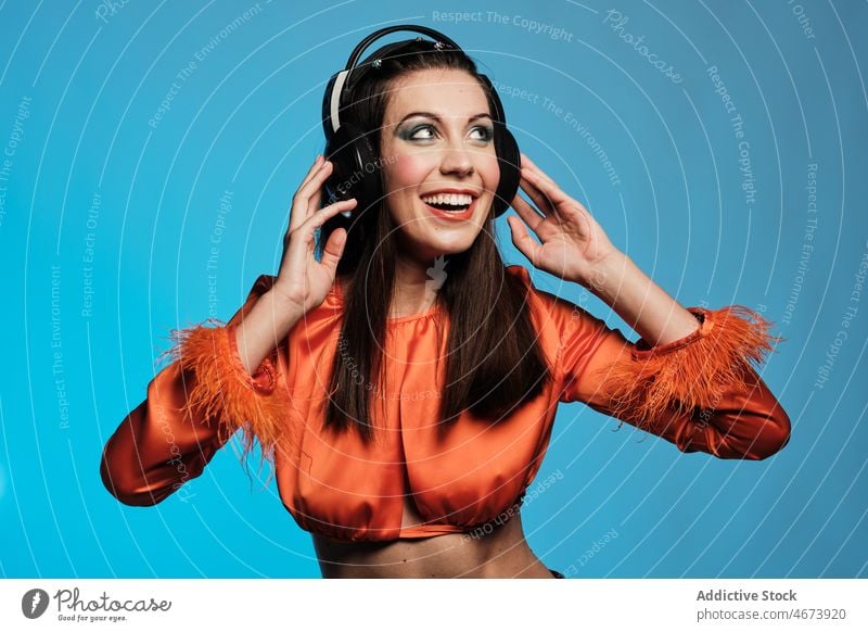 Smiling woman in headphones singing in studio song music vocalist smile cheerful hobby makeup playlist sound style fashion design trendy appearance happy