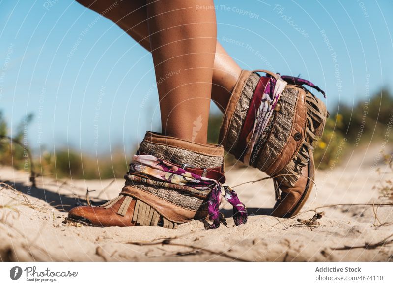 Tanned woman in boots standing on sandy beach traveler coast shore trip summer holiday female tourist style vacation nature seashore tourism journey coastline