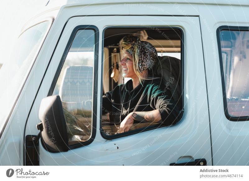 Through window of positive woman in camping van rest recreation traveler camper road trip drive driver trailer vehicle transport caravan auto female lady summer