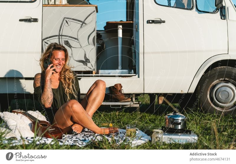 Woman talking on smartphone near camping van woman phone call conversation speak chat smile hipster traveler camper road trip trailer cheerful hippie vehicle