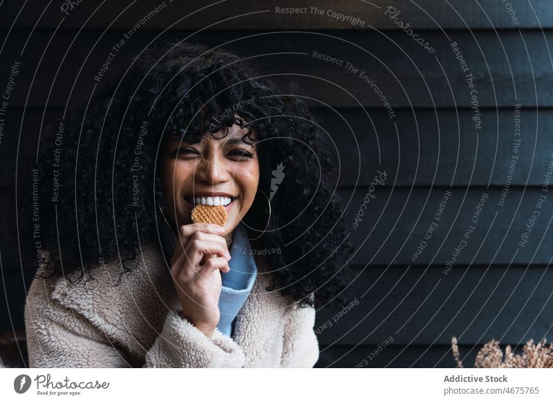 Cheerful black woman eating cookie dessert enjoy delicious sweet waffle toothy smile chill female african american woman positive happy cheerful tasty