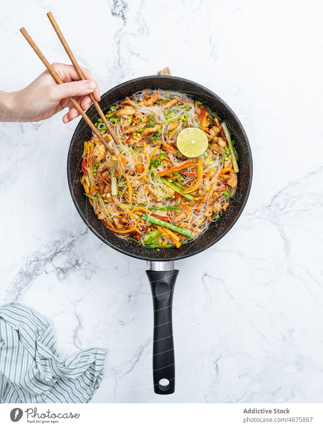 Anonymous person eating stir fry rice noodles with vegetables chopstick meal culinary cuisine food delicious tasty dish hungry appetite dinner yummy gastronomy