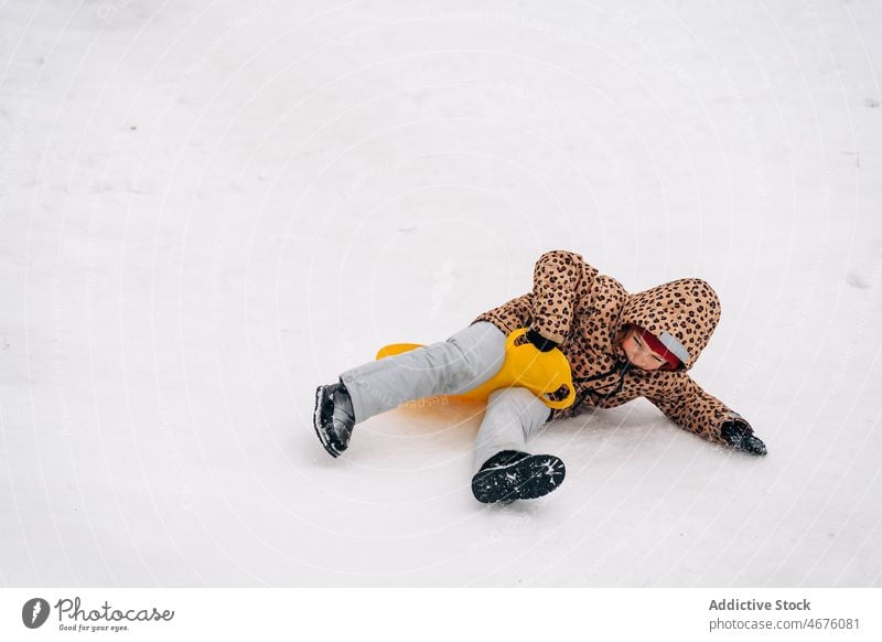 Cheerful kid on snow saucer childhood ride sled hill winter having fun playful amusement season frost outerwear cold enjoy cheerful wintertime happy weather