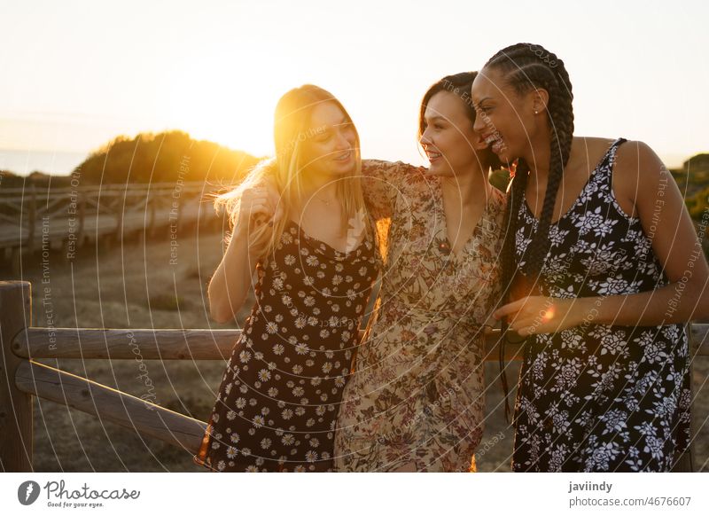 Joyful multiethnic women embracing near fence friend leisure bonding rest recreation waterfront hug embrace tender cuddle relationship pastime diverse