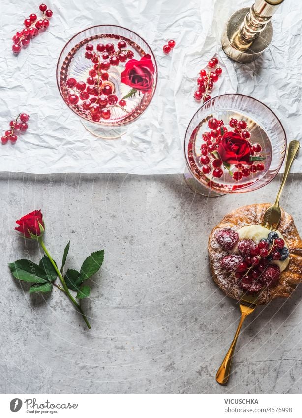 Valentines day with sparkling wine in champagne glass and red currants, rose petals valentines day pastry pudding berries table romantic breakfast top view